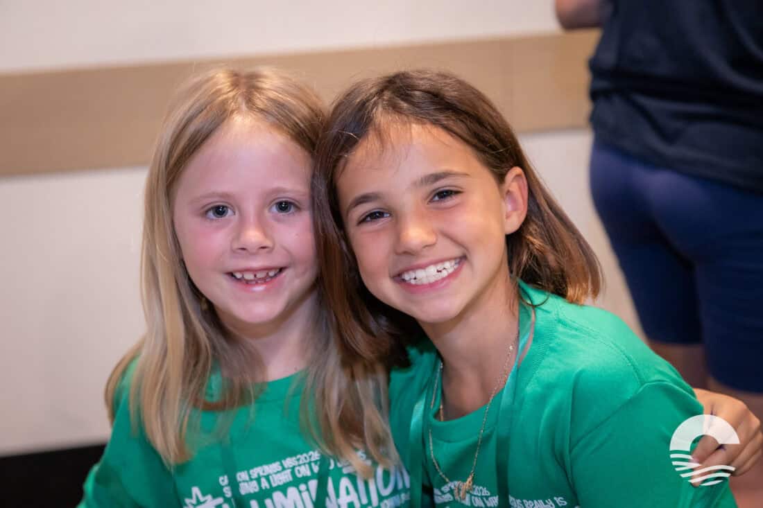 Two smiling young girls at Canyon Springs Church event, wearing green shirts.