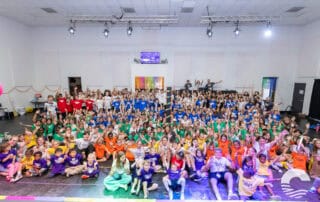 Large group of children and adults gathered in a church hall for a community event.
