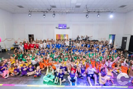 Large group of children and adults gathered in a church hall for a community event.