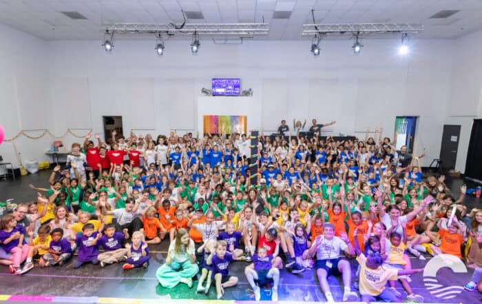 Large group of children and adults gathered in a church hall for a community event.