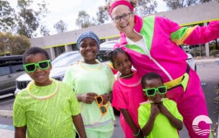 Happy children with sunglasses and a woman in colorful sportswear.