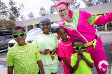Happy children with sunglasses and a woman in colorful sportswear.