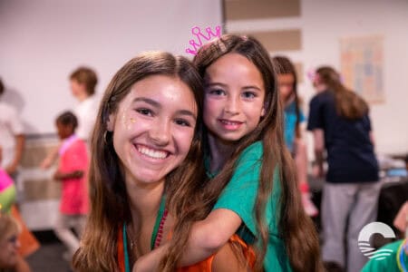 Two smiling girls at Canyon Springs Church youth event, one with a pink crown headband.