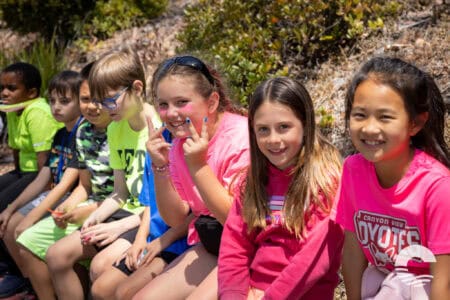 Group of smiling children sitting outdoors at Canyon Springs Church event.