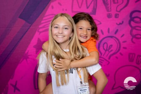 Two smiling girls hugging at Canyon Springs Church kids event.