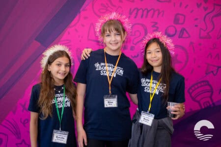 Three smiling girls in matching shirts and pink tinsel headbands at Canyon Springs Church youth even.