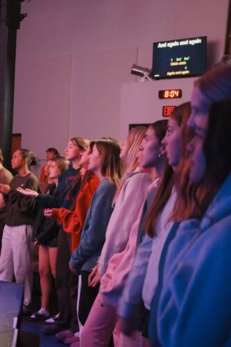 Attendees of Canyon Springs Church standing in prayer during a service, demonstrating community and faith. Diverse congregation attending service at Canyon Springs Church.