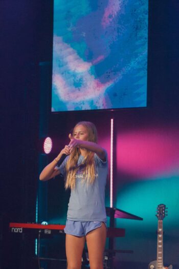 Young girl singing and playing guitar during youth worship at Canyon Springs Church.