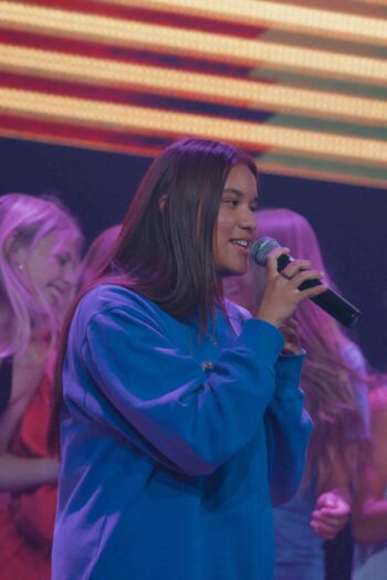 Young woman singing into a microphone during youth worship service at Canyon Springs Church.