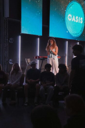 Young woman speaking on stage at Canyon Springs Church youth event.