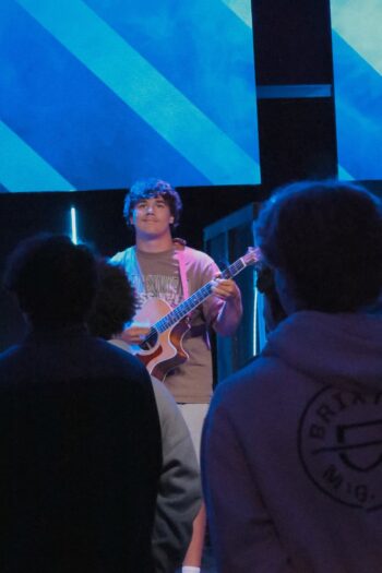 Young man playing acoustic guitar during youth worship at Canyon Springs Church.