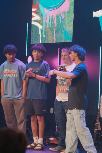 Four teenagers on stage during a youth worship night at Canyon Springs Church, engaging in a musical or spiritual activity. Teenagers participating in youth worship night at Canyon Springs Church stage.