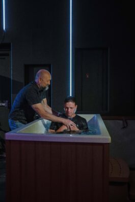 A baptism ceremony at Canyon Springs Church with a man baptizing a young individual in the baptismal pool. Man baptizing a young person in a baptismal pool at Canyon Springs Church.